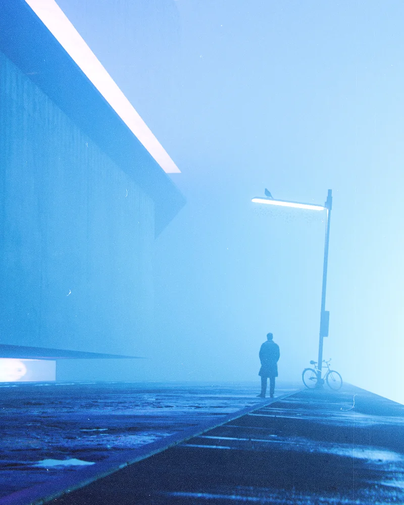 A lone figure under a street lamp in blue fog